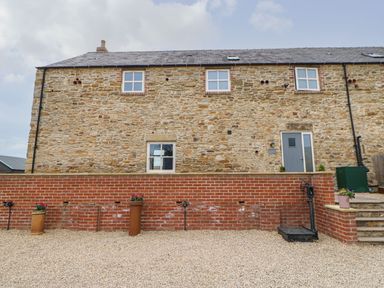 A stone wall building with windows and door in a gravel area at The Granary Durham