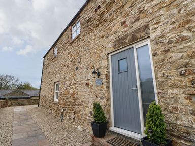 An exterior view of a stone wall with a door and planters at The Granary in Durham