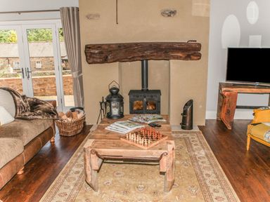 A living room with a sofa, coffee table, fireplace, and television at The Granary in Durham