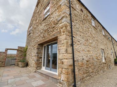 An outdoor area with stone walls and a paved pathway at The Granary in Durham