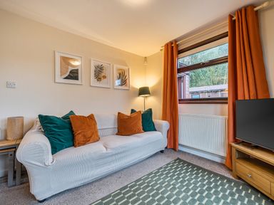 A living room with a sofa, lamp, pictures and television at Cabin 1 Moffat Manor Beaufort