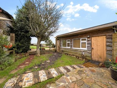 An outdoor view of a cabin with a tree and pathway at The Retreat Cabin in Llanelli
