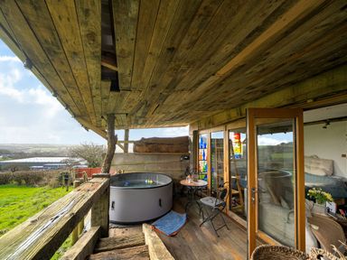 An outdoor area with a hot tub and chairs at The Retreat Cabin in Llanelli