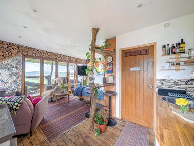 A living room with a sofa, table, and television at The Retreat Cabin in Llanelli