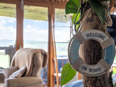 A lifebuoy hanging next to a plant and a chair at The Retreat Cabin in Llanelli