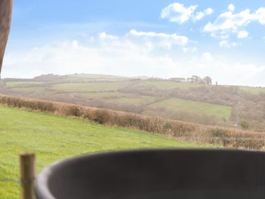 A view of hills and fields with a house in the distance at The Retreat Cabin in Llanelli