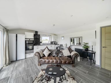 A living room with a couch and kitchen appliances at The lodge at Plumstone View in Letterston