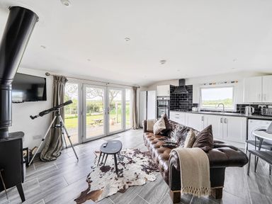 A living room with a television, sofa, and telescope at The lodge at Plumstone View in Letterston