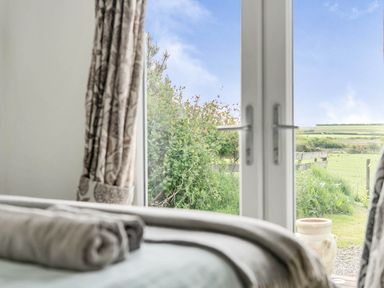 A view from a bedroom window with curtains and towels at The lodge at Plumstone View in Letterston