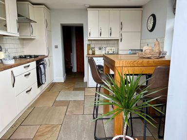 A kitchen with cabinets and a table at Penderyn Cottage Aberdare