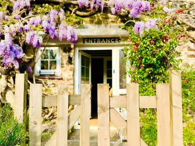 An entrance with a wooden gate and flowers at The Bark House in Tiverton