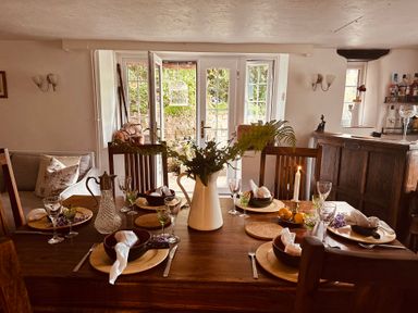 A dining room with a table set for a meal at The Bark House in Tiverton