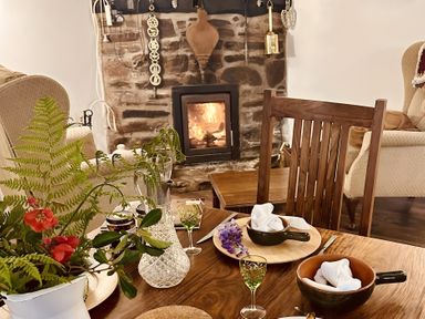 A dining room with a fireplace and a wooden table set at The Bark House in Tiverton