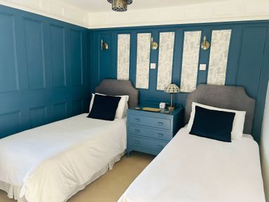 A bedroom with two beds and a lamp on a nightstand at The Bark House in Tiverton
