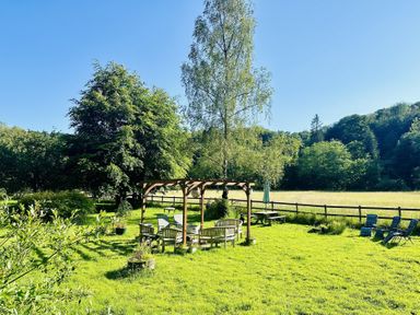 An outdoor seating area with a pergola and trees at The Bark House in Tiverton