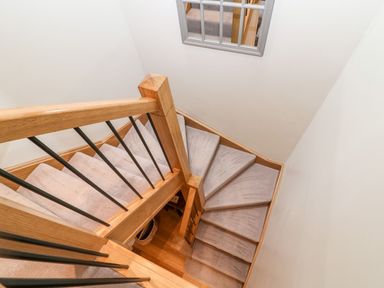 A staircase with wooden handrail and carpet at East View in Cheltenham
