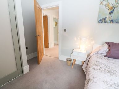 A bedroom with a bed, lamp, and nightstand at East View Cheltenham