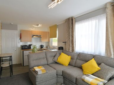 A living room with a sofa and kitchen area at 228b Eighth Avenue Bridlington