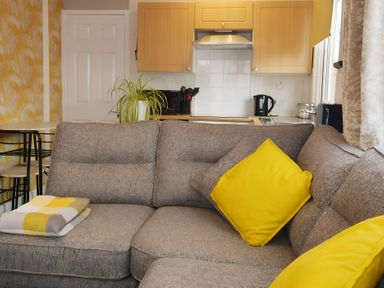 A living room with a sofa and kitchen area at 228b Eighth Avenue in Bridlington