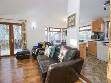 A living room with a sofa, armchair, and kitchen units at 6 Waterside Windermere