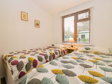 A bedroom with two beds and a bedside table at 6 Waterside, White Cross Bay near Windermere
