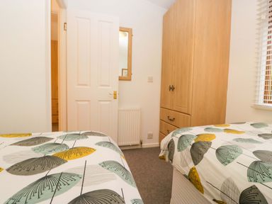 A bedroom with two beds and a wardrobe at 6 Waterside, White Cross Bay near Windermere