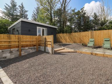 A garden with gravel area and wooden fence at Heidiaway Lodge in Gilfach Goch
