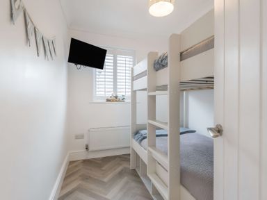 A bedroom with a bunk bed and television at 6 Tegafan Abergele