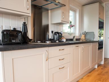 A kitchen with cabinets and appliances at Nethermill Lodges in Port Glasgow