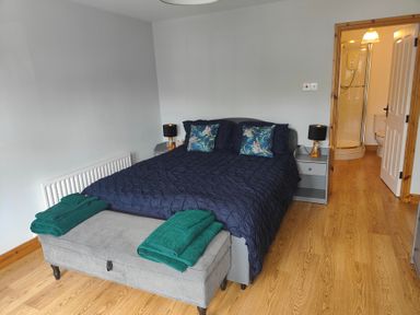 A bedroom with a bed, nightstands, towels, and a shower at 17 Castleview in Ballymena