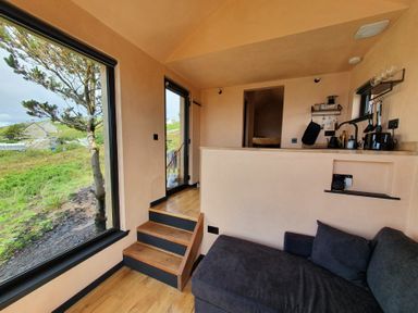 A living room with a sofa and kitchen counter at Cullinview in Isle of Skye