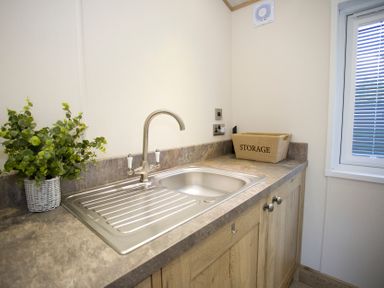 A kitchen area with a sink and storage box at Orchid 9 Christchurch