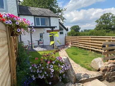 A garden with flowers, a table, and chairs at The Haven in Penrith