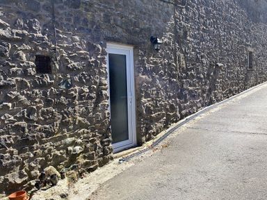 An outdoor view of a stone wall with a door and light fixture at The Haven in Penrith