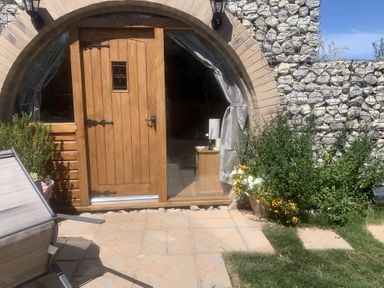 An entrance with a wooden door and flowers at Cosy Escape in Sheerness