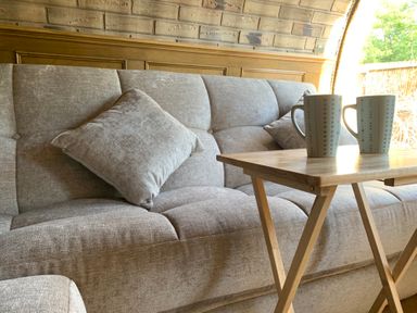 A sofa with a cushion and a table with mugs at Cosy Escape Sheerness