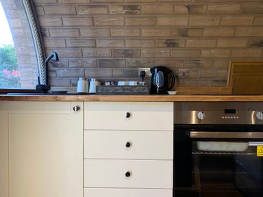 A kitchen with sink kettle and oven at Cosy Escape Sheerness