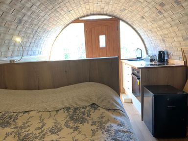 A bedroom with a kitchen area and a doorway at Cosy Escape in Sheerness