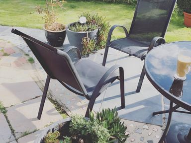 A garden with chairs, a table, and plants at Cosy Escape in Sheerness