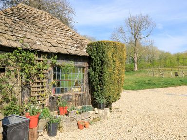 A garden view of a house with plants and gravel pathway at Foxhill Farm Barn in Cheltenham