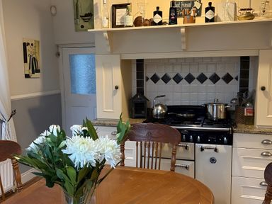 A kitchen with a stove and table with flowers at Fountain Hill House in Londonderry