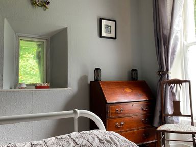 A bedroom with a window and wooden furniture at Fountain Hill House in Londonderry