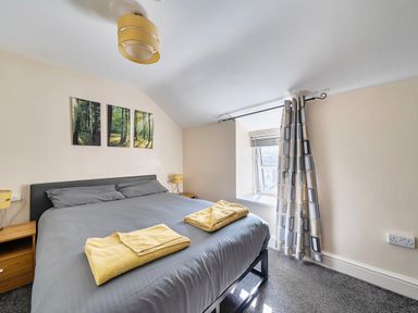 A bedroom with a bed and wall art at Sea view cottage in Penmaenmawr