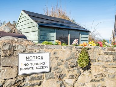 An outdoor shed with a stone wall and sign at Sea view cottage in Penmaenmawr