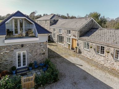 A stone house with multiple windows and a gravel pathway at Poppyfields Stable Redruth