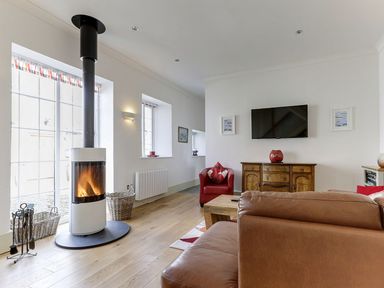 A living room with a wood stove and sofa at Poppyfields Stable in Redruth