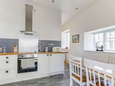 A kitchen with modern appliances and a dining table at Poppyfields Stable in Redruth
