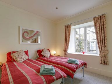 A bedroom with two beds and a window at Poppyfields Stable in Redruth