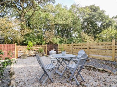 A garden with a table and chairs surrounded by gravel at Poppyfields Stable in Redruth