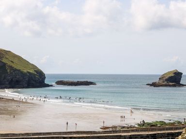A beach with people walking and swimming near rocks at Poppyfields Stable Redruth